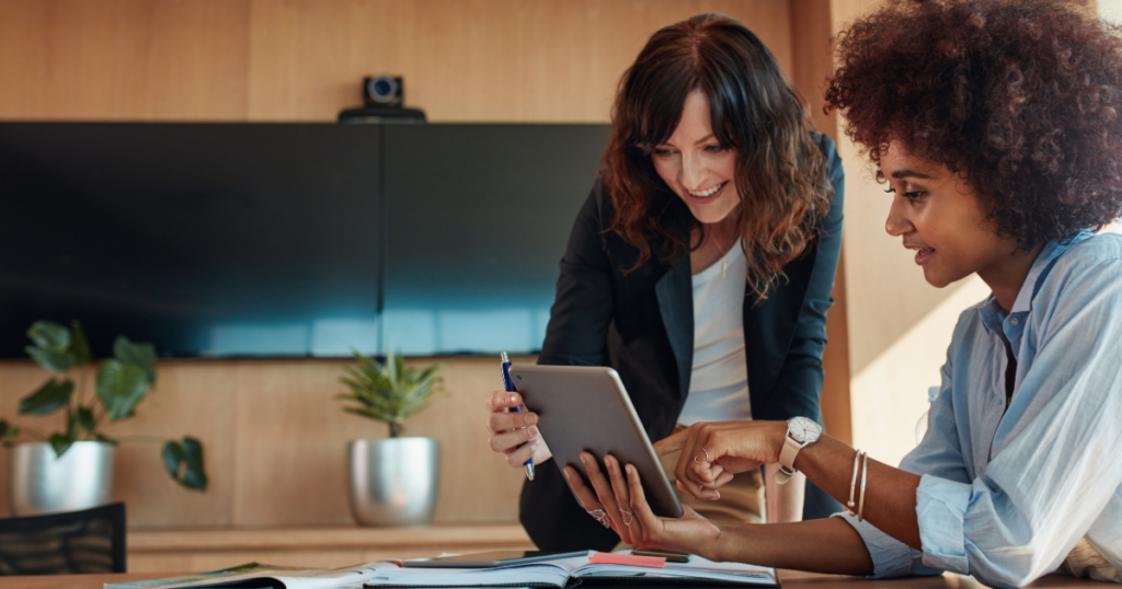 Two women looking at a tablet that could contain an employee handbook