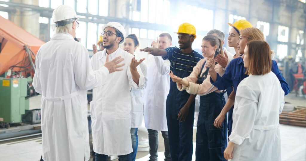 Mitarbeitende in einer Fabrik reden aufgebracht auf einen Vorgesetzten ein