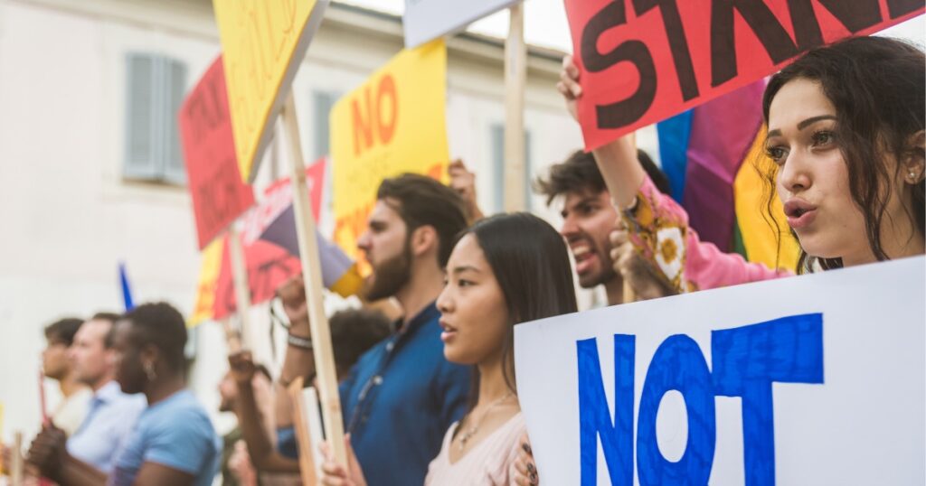 Demonstrant*innen mit Schildern protestieren auf der Straße