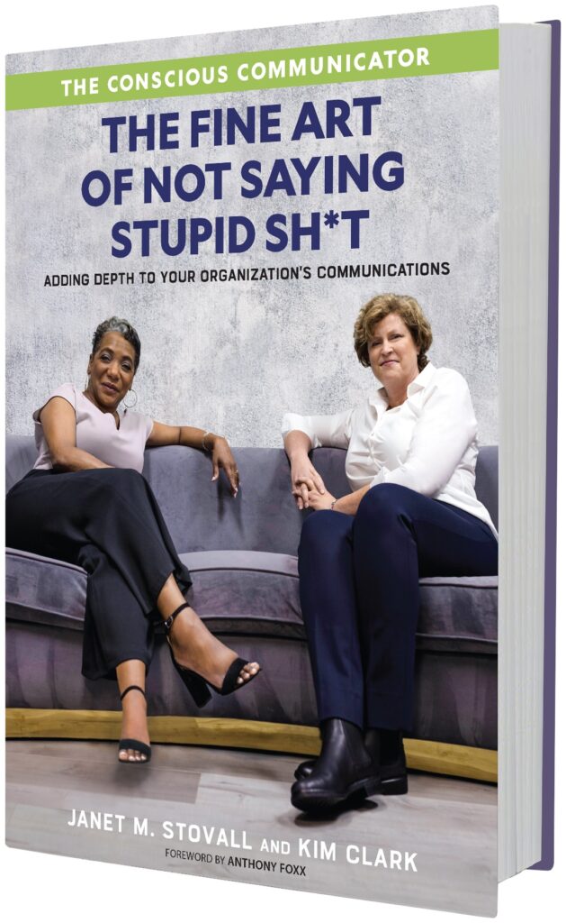 Janet M. Stovall and Kim Clark sit on a purple couch and look directly at the camera. The title of the book, "The Conscious Communicator: The Fine Art of Not Saying Stupid Sh*t" is above their heads. Underneath the title reads the subtitle: "Adding DEPTH to your organizaiton's communications."