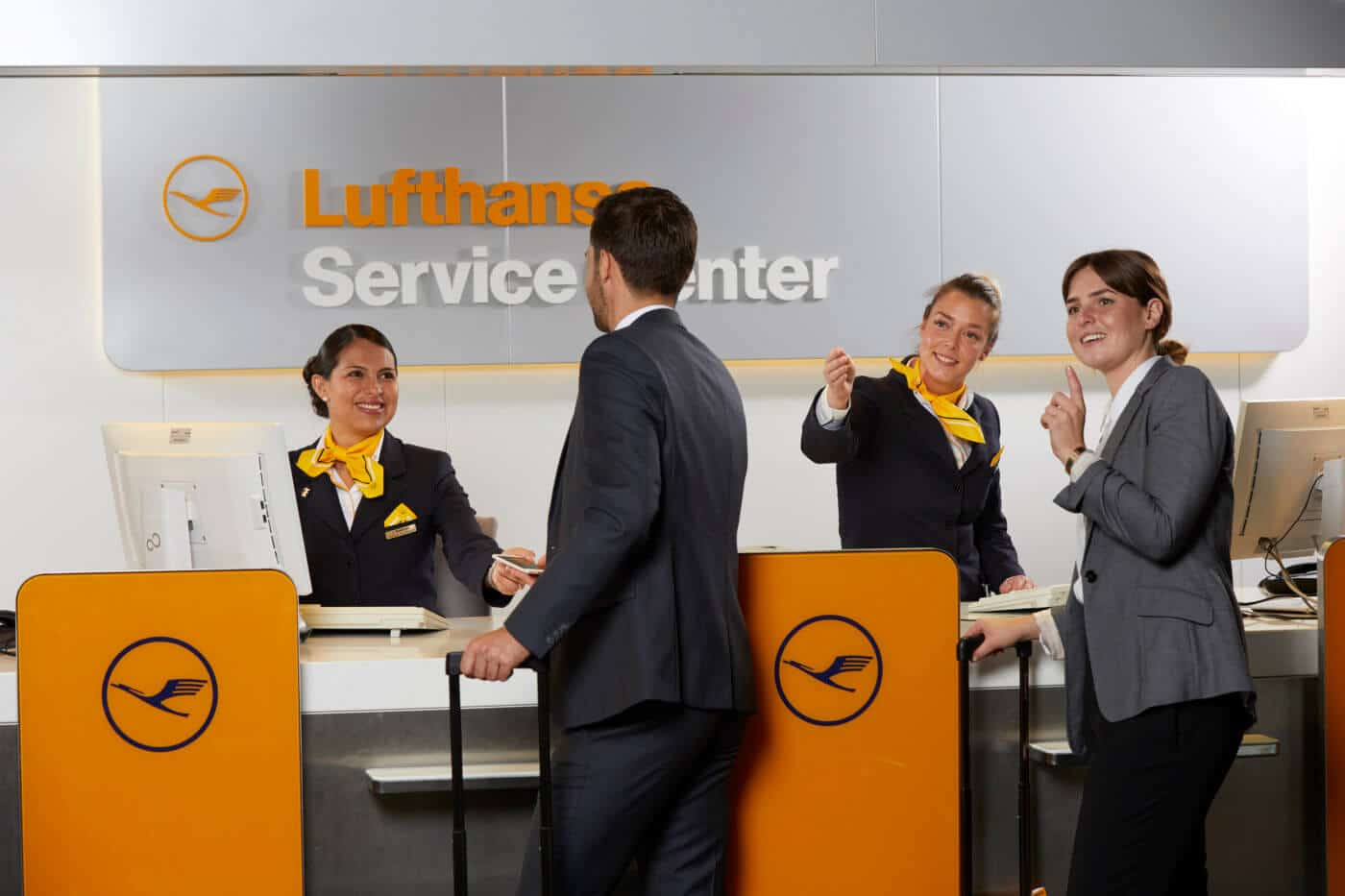 Mitarbeiterinnen eines Lufthansa Services Centers geben zwei Fluggästen eine Auskunft