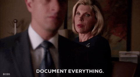 A woman with short blonde hair and a black dress with a dragonfly pendant says "Document everything" to a man in a suit as he walks out of the frame
