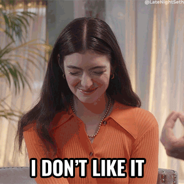 Singer Lorde closes her eyes and shakes her head. The text "I don't like it" appears underneath her. She is wearing an orange long sleeve shirt and has long dark brown hair. 