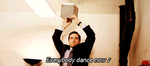 Michael Scott from the office dances on a chair and holds a speaker up to the ceiling while singing "Everybody dance now!"