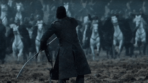 GIF of Jon Snow from Game of Thrones drawing his sword against approaching soldiers on horses.