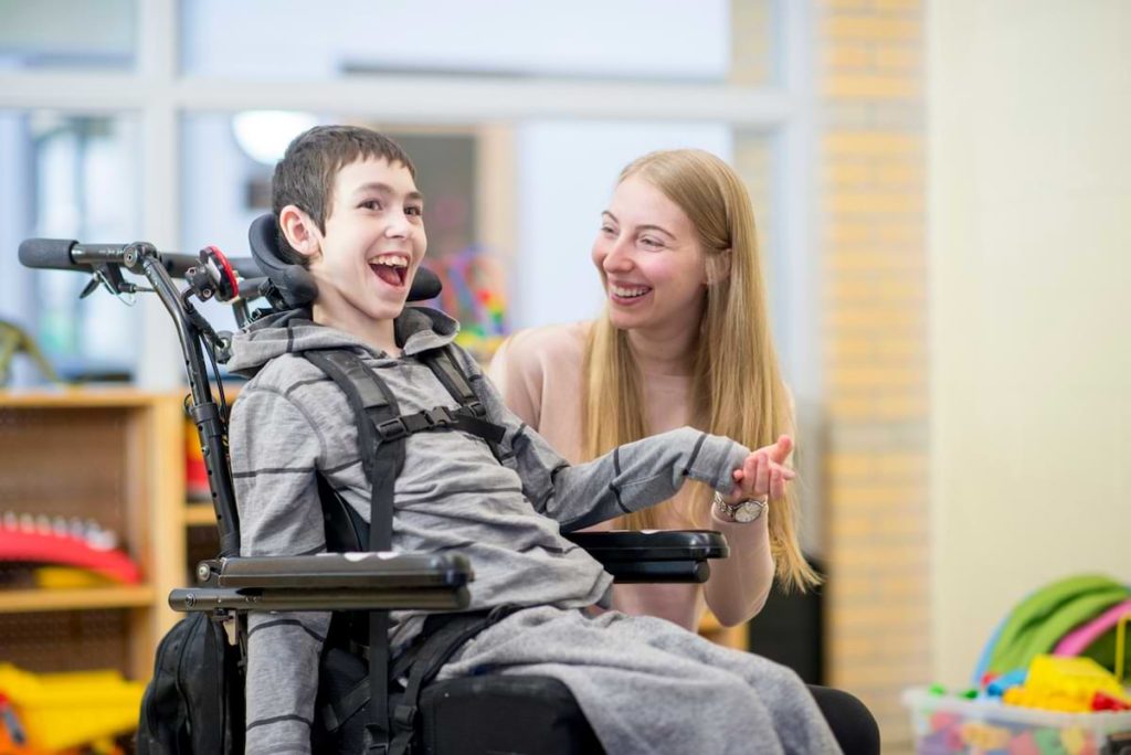 A photograph of a caregiver smiling with a disabled child.