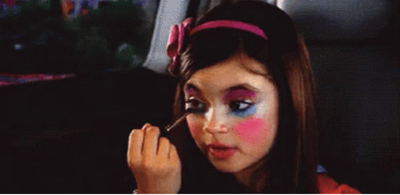 A young girl puts a lot of make-up on her face