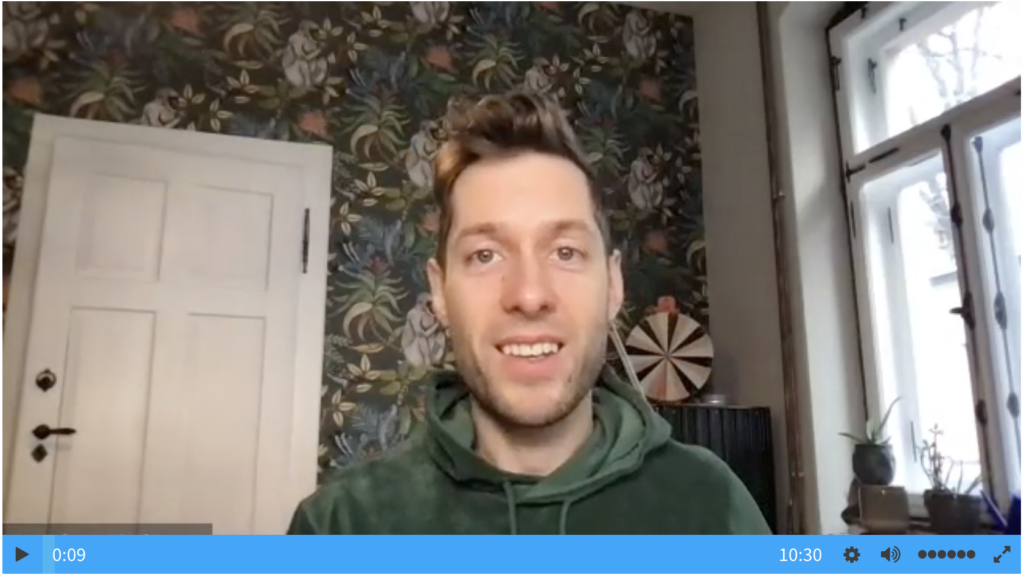 Staffbase CEO answers employee questions through an Ask Me Anything session. He sits in his home facing the camera, smiling. His backdrop is his signature jungle patterned wallpaper. 