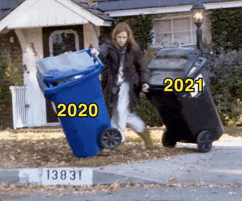 woman wrestling with two garbage cans spilling out onto the street, one is labelled 2020, one is labeled 2021
