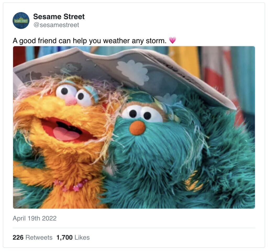 Two Sesame Street muppets share a newspaper, held over their heads to shelter them from rain. 