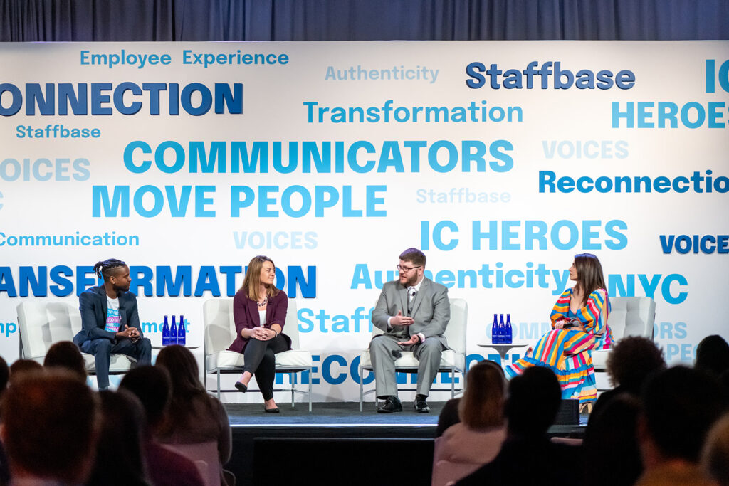 Esaue Conway of Staffbase sits down with panelists Lindsay Theile, Bret Roberts, and Adrienne Hoyt on the NYC VOICES stage. Audience members watch on as Bret talks.